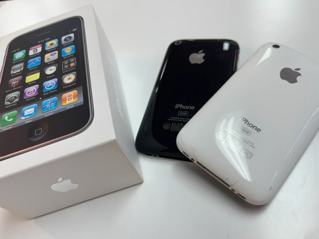 iPhone 3Gの黒と白の本体、元箱付きで机に並べられた買取査定のシーン。
